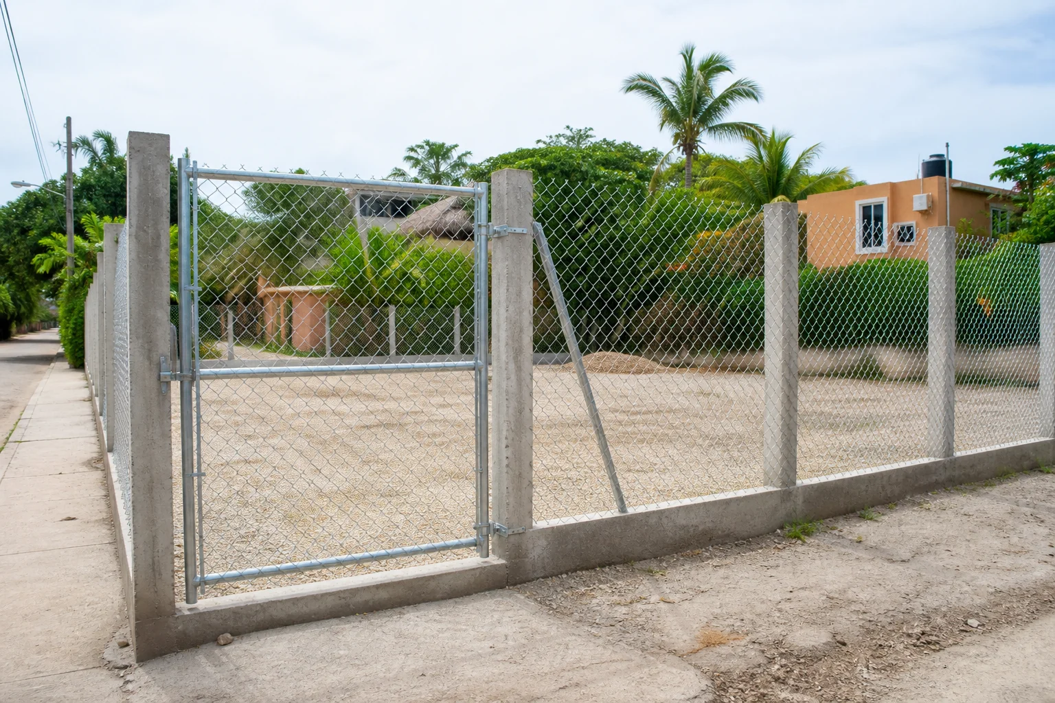 Cerca de malla galvanizada tipo ciclónica con acceso peatonal sobre postes de concreto